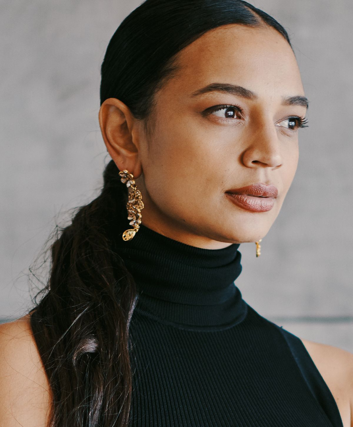 Woman with elegant earrings and black turtleneck.
