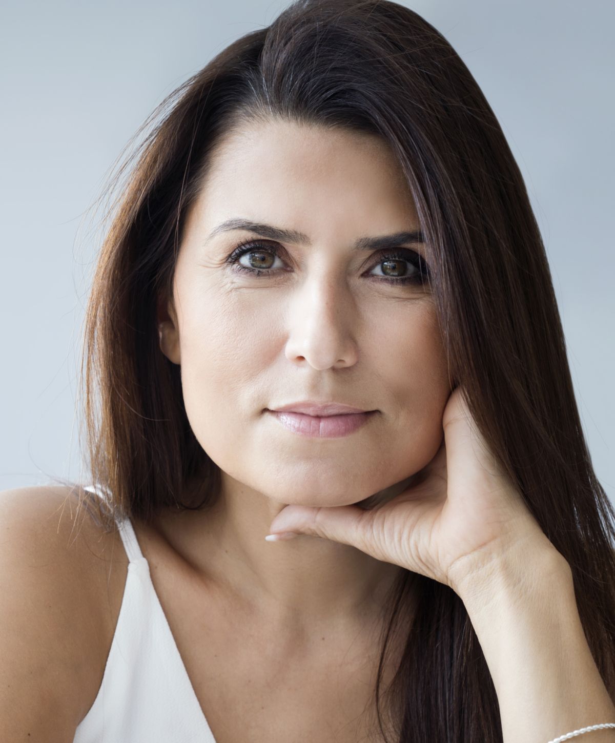 Woman posing thoughtfully with hand on chin.