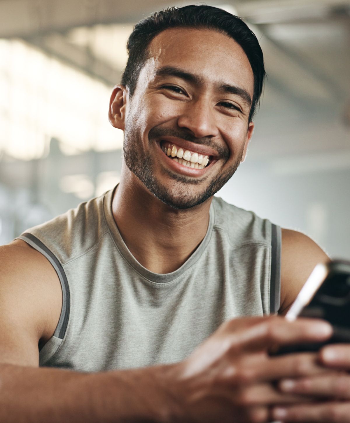 Smiling Mission Viejo BioTE model holding a phone in a gym.