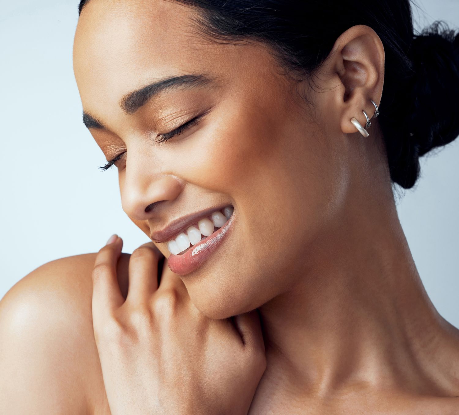 Smiling Orange County med spa model with elegant earrings and radiant skin.