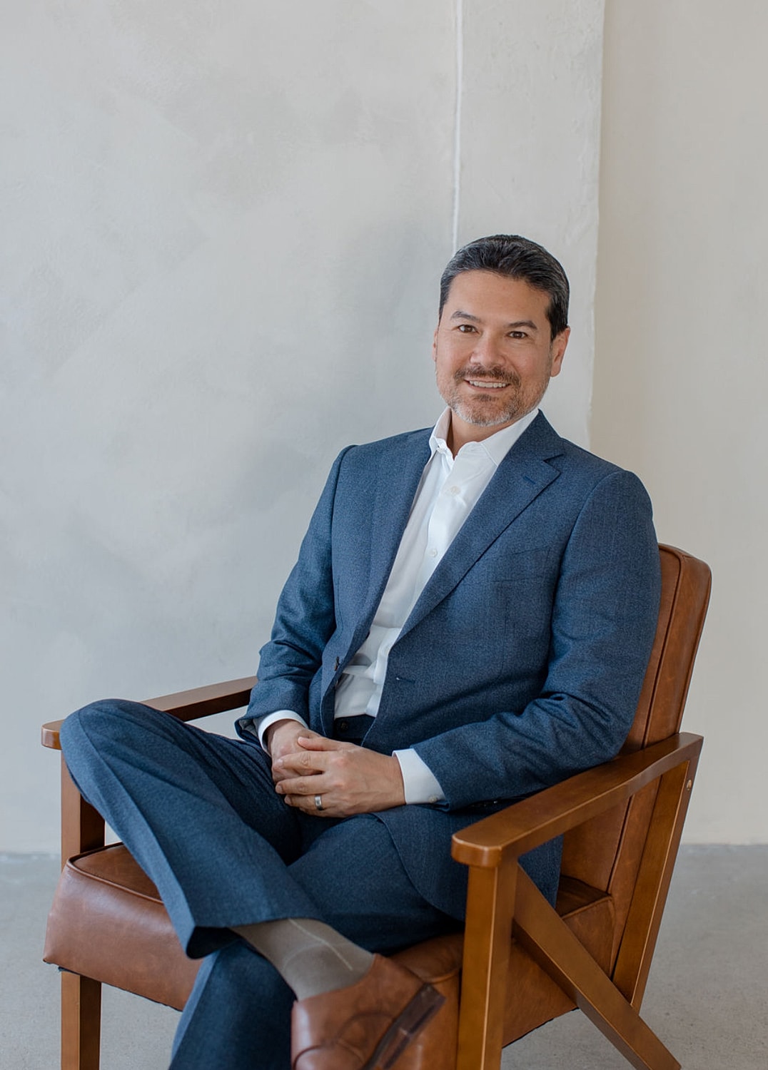Orange County med spa owner on a white couch with decorative background.