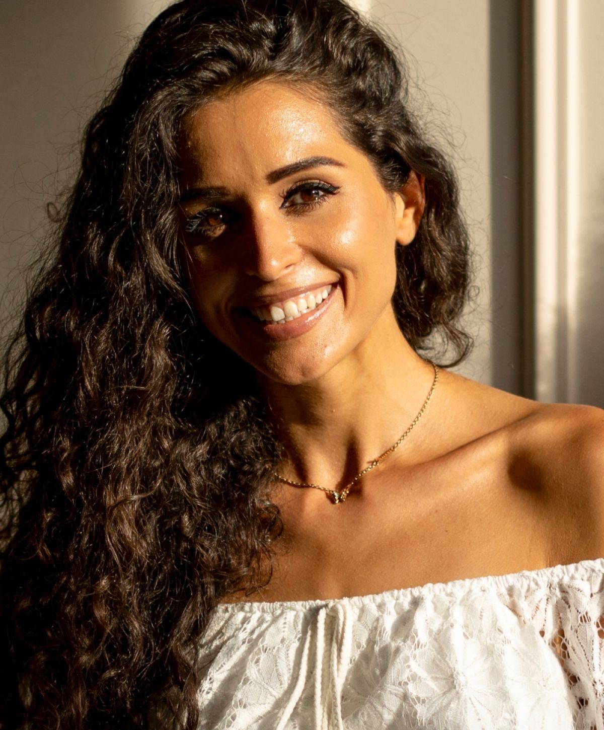 Smiling Lake Forest med spa model with curly hair in sunlight.