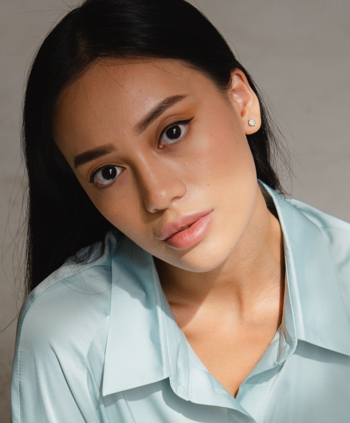 Young Ladera Ranch med spa model in a light blue shirt, thoughtfully gazing.