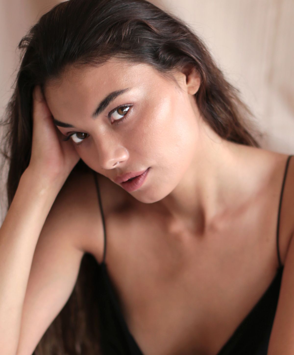 Orange County facial model with long hair resting her head.