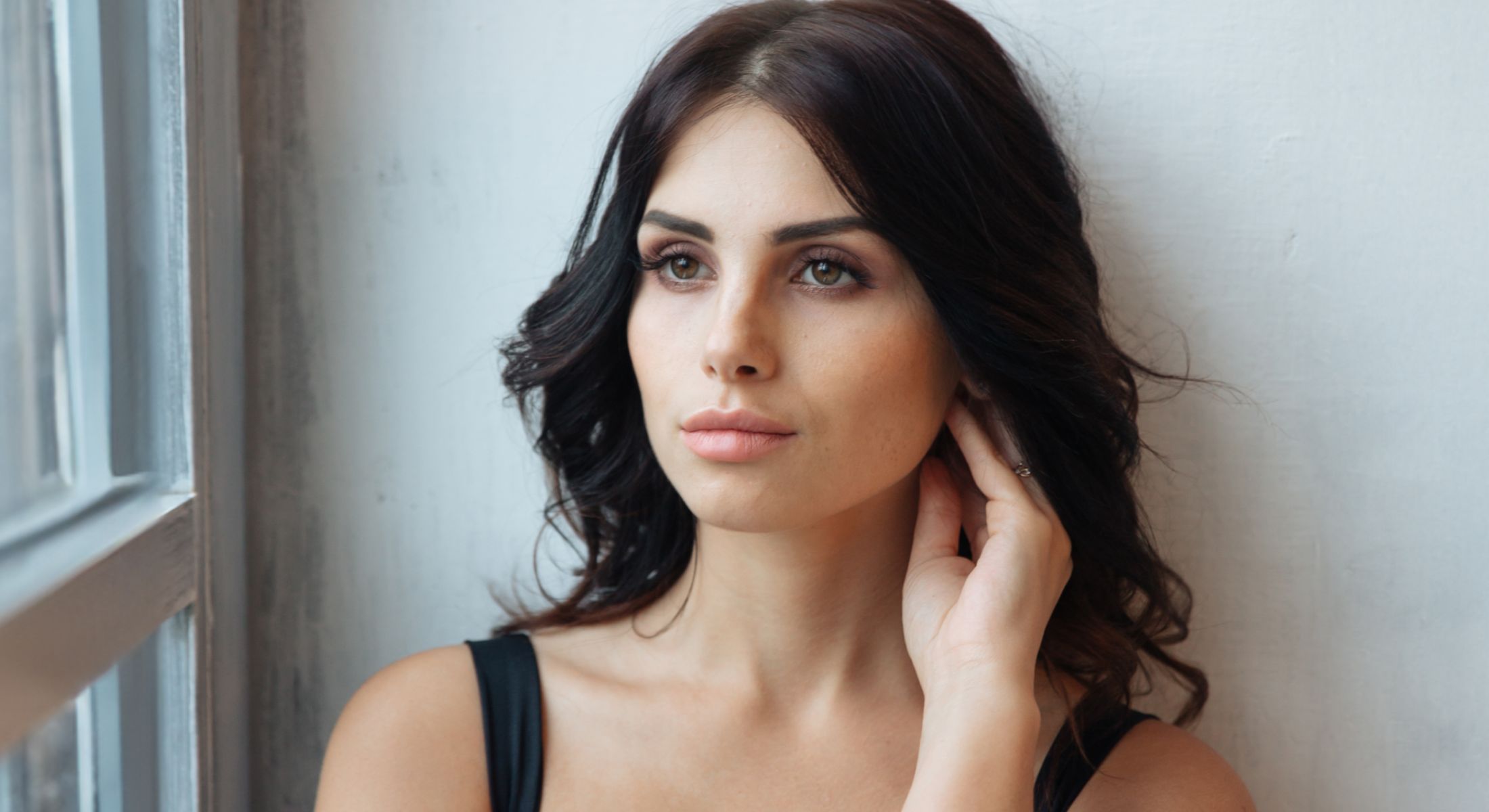 Portrait of a Mission Viejo dermal fillers model with dark wavy hair.