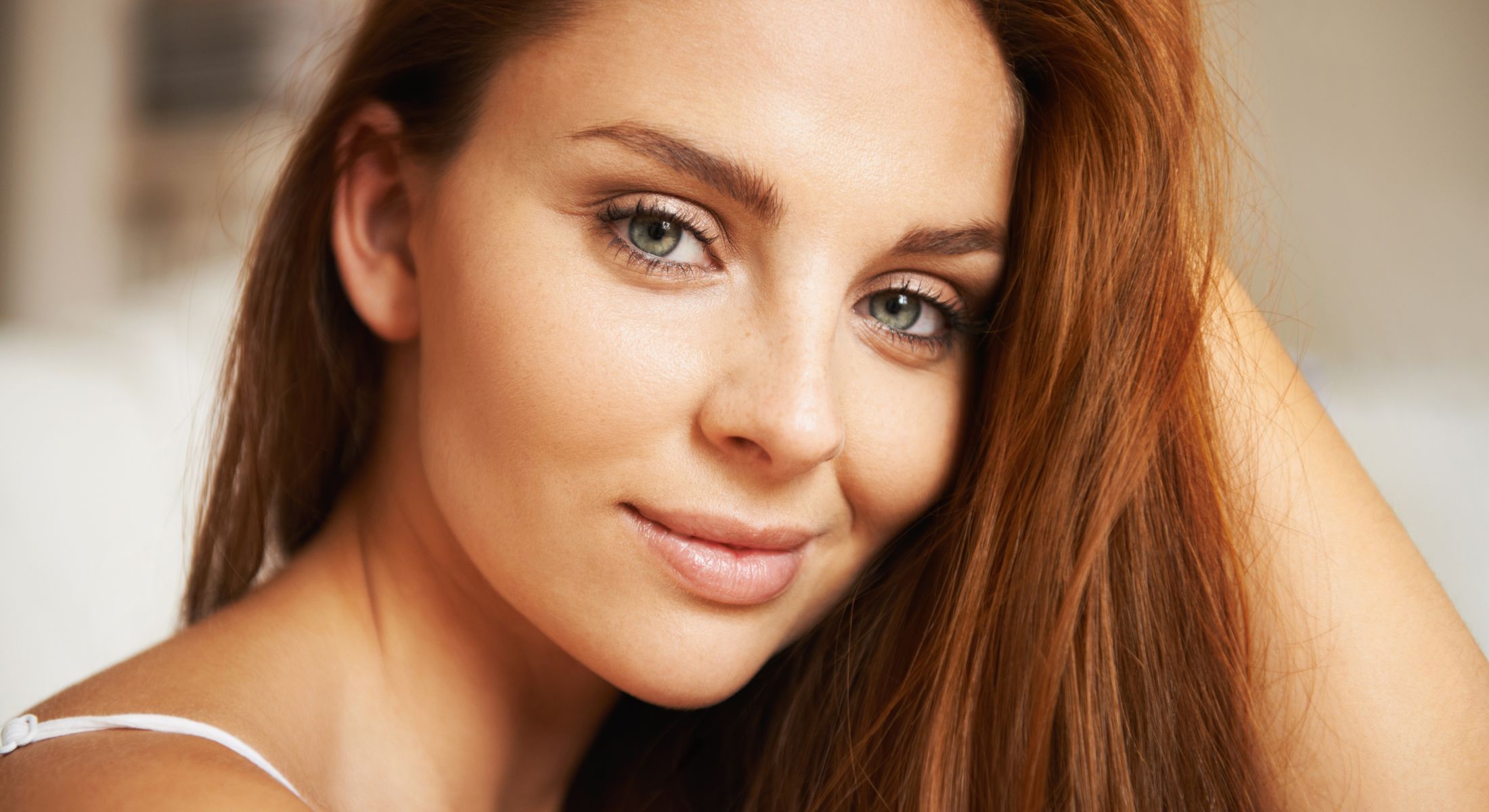 Close-up of San Juan Capistrano dermal fillers model with long, reddish hair.