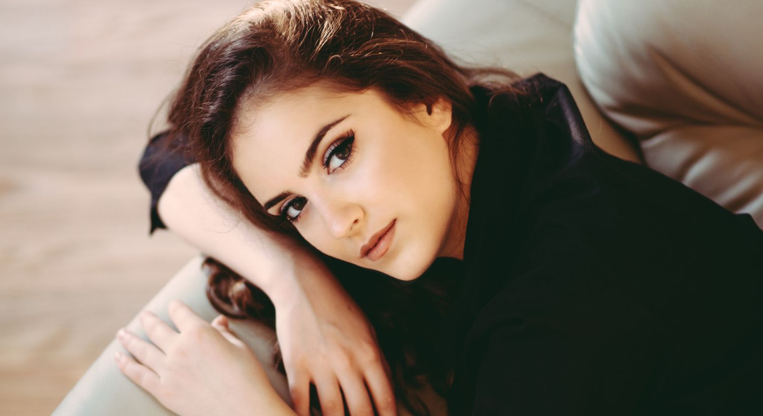 Orange County HRT model lounging on a couch, thoughtful expression.